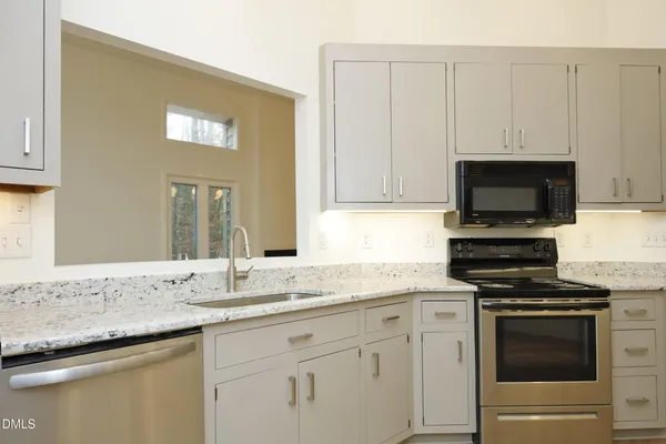a kitchen with granite countertop white cabinets and stainless steel appliances