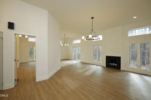 a view of a livingroom with wooden floor a ceiling fan and windows