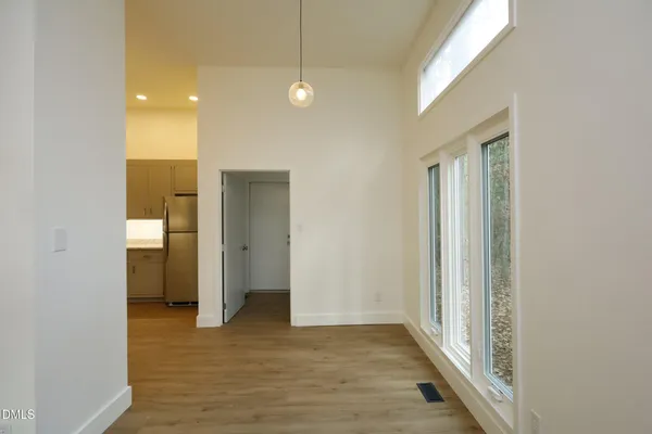 a view of a hallway with wooden floor and a bathroom