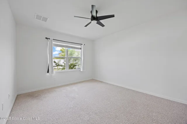 an empty room with windows and ceiling fan view