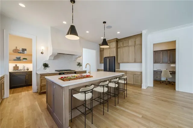 a kitchen with stainless steel appliances granite countertop a stove a sink a refrigerator and a dining table with wooden floor