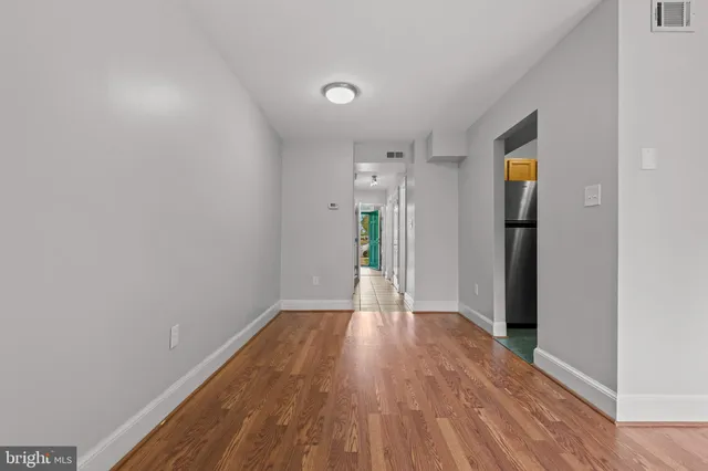an empty room with windows a fireplace and wooden floor