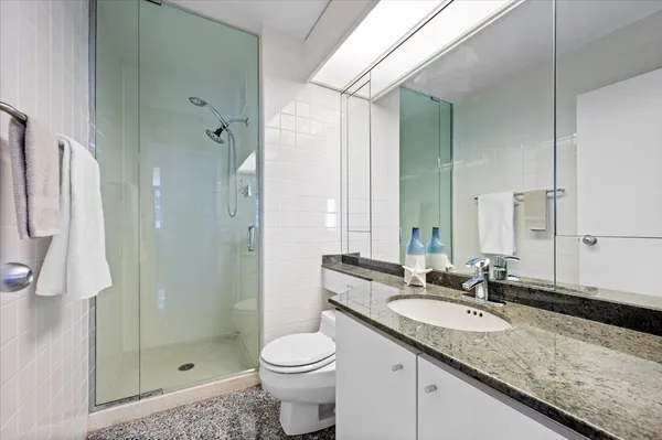 a bathroom with a granite countertop sink a toilet and shower
