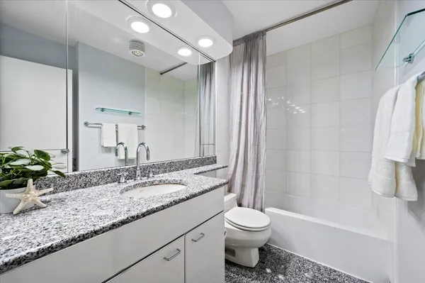 a bathroom with a granite countertop sink toilet and shower