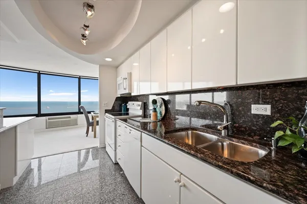 a kitchen with kitchen island granite countertop a sink a counter top space cabinets and stainless steel appliances