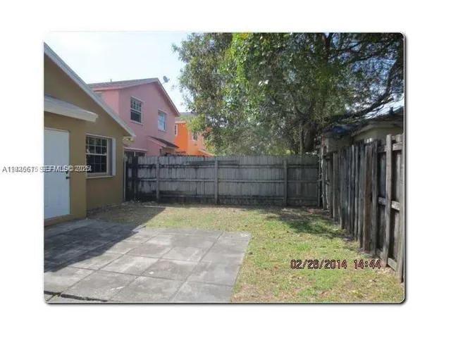 a view of backyard with wooden fence and large trees