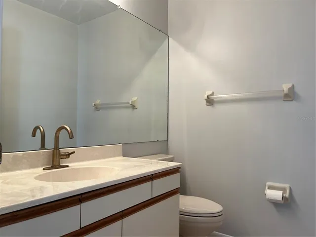 a bathroom with a granite countertop sink a toilet and a mirror