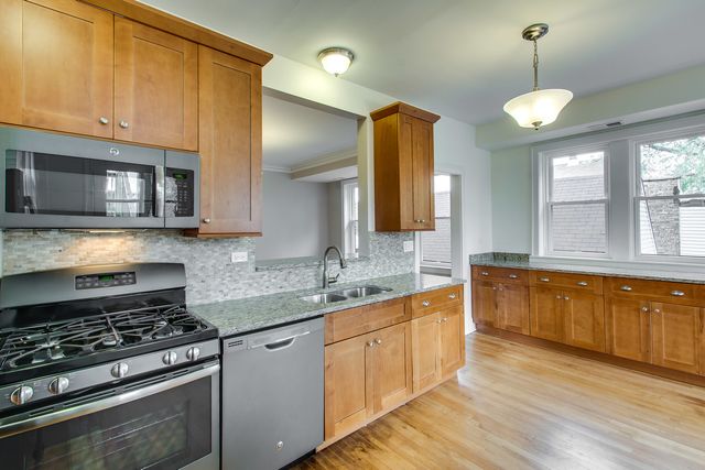 a large kitchen with cabinets a sink dishwasher and a large window