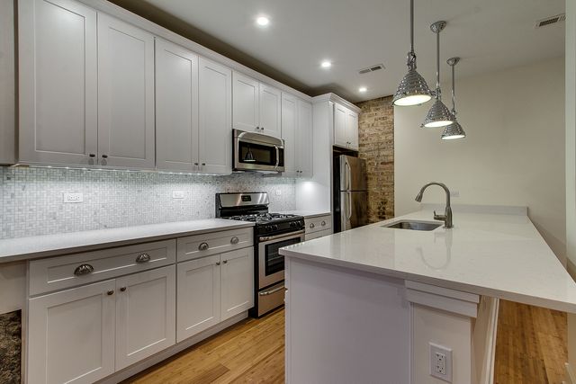 a kitchen with kitchen island granite countertop stainless steel appliances a sink a stove and a microwave