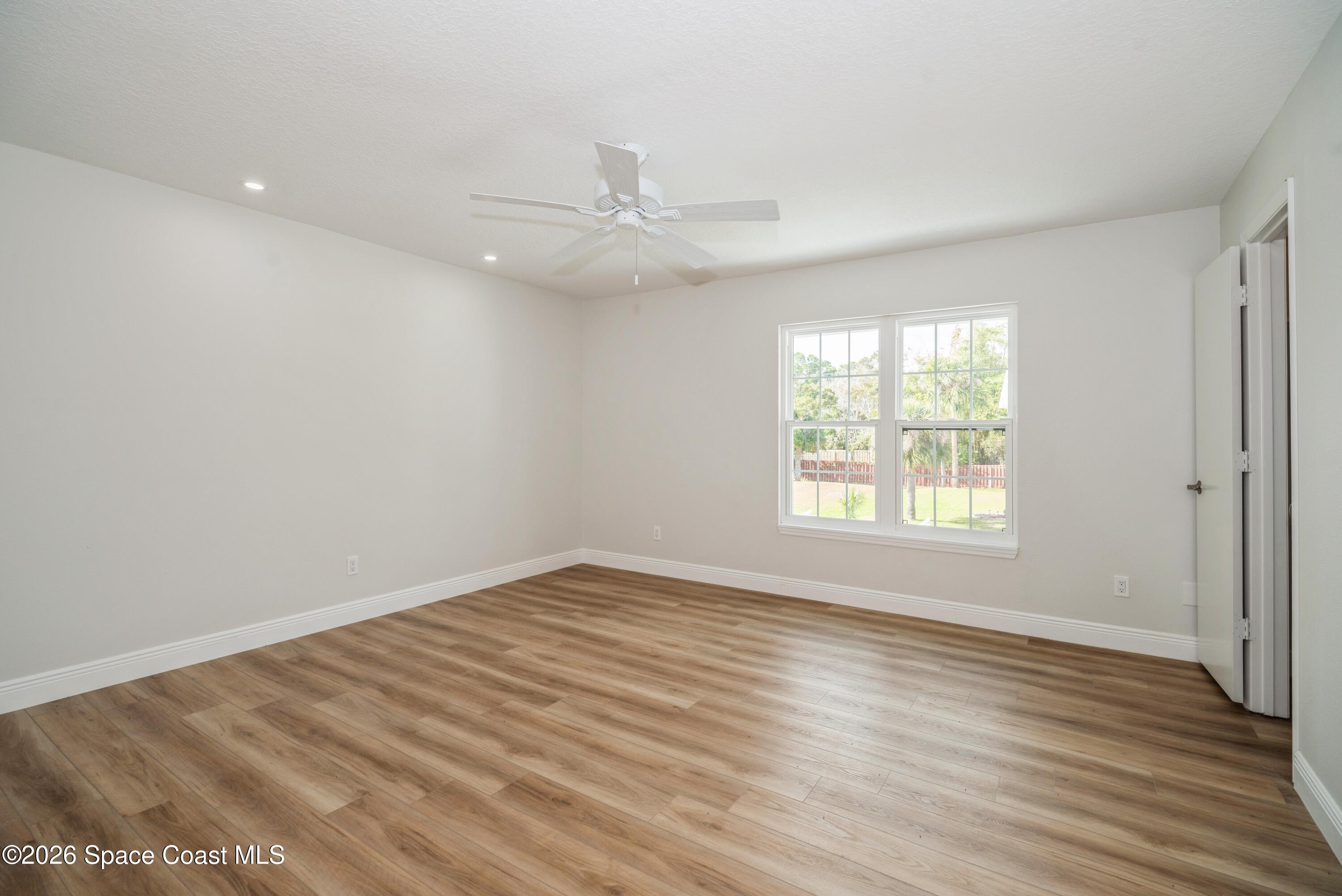 2018 Manor Drive Northeast Palm Bay, FL 32905 - Photo 17 of 29 an empty room with wooden floor fan and windows