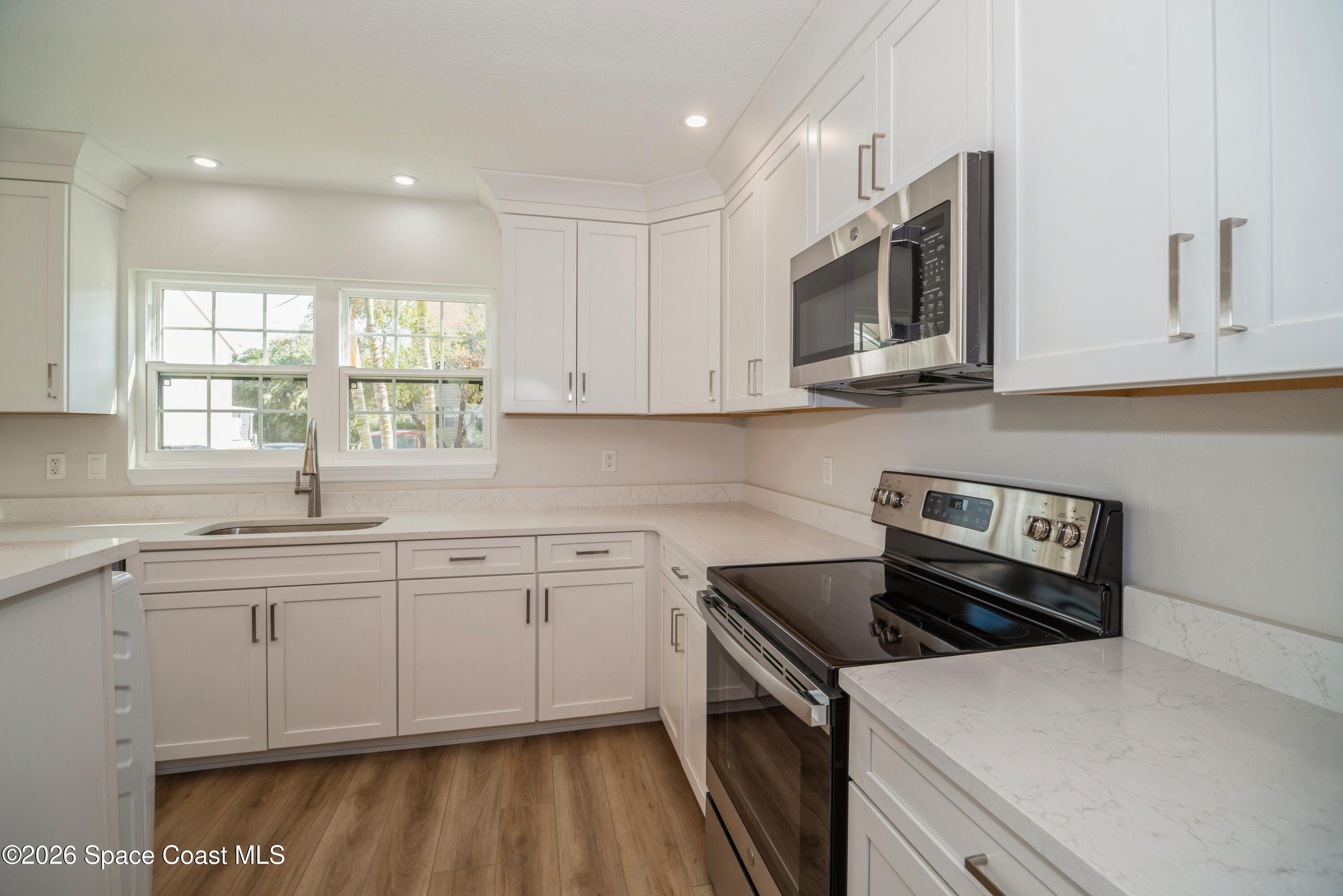 2018 Manor Drive Northeast Palm Bay, FL 32905 - Photo 5 of 29 a kitchen with stainless steel appliances granite countertop a stove a sink and a microwave