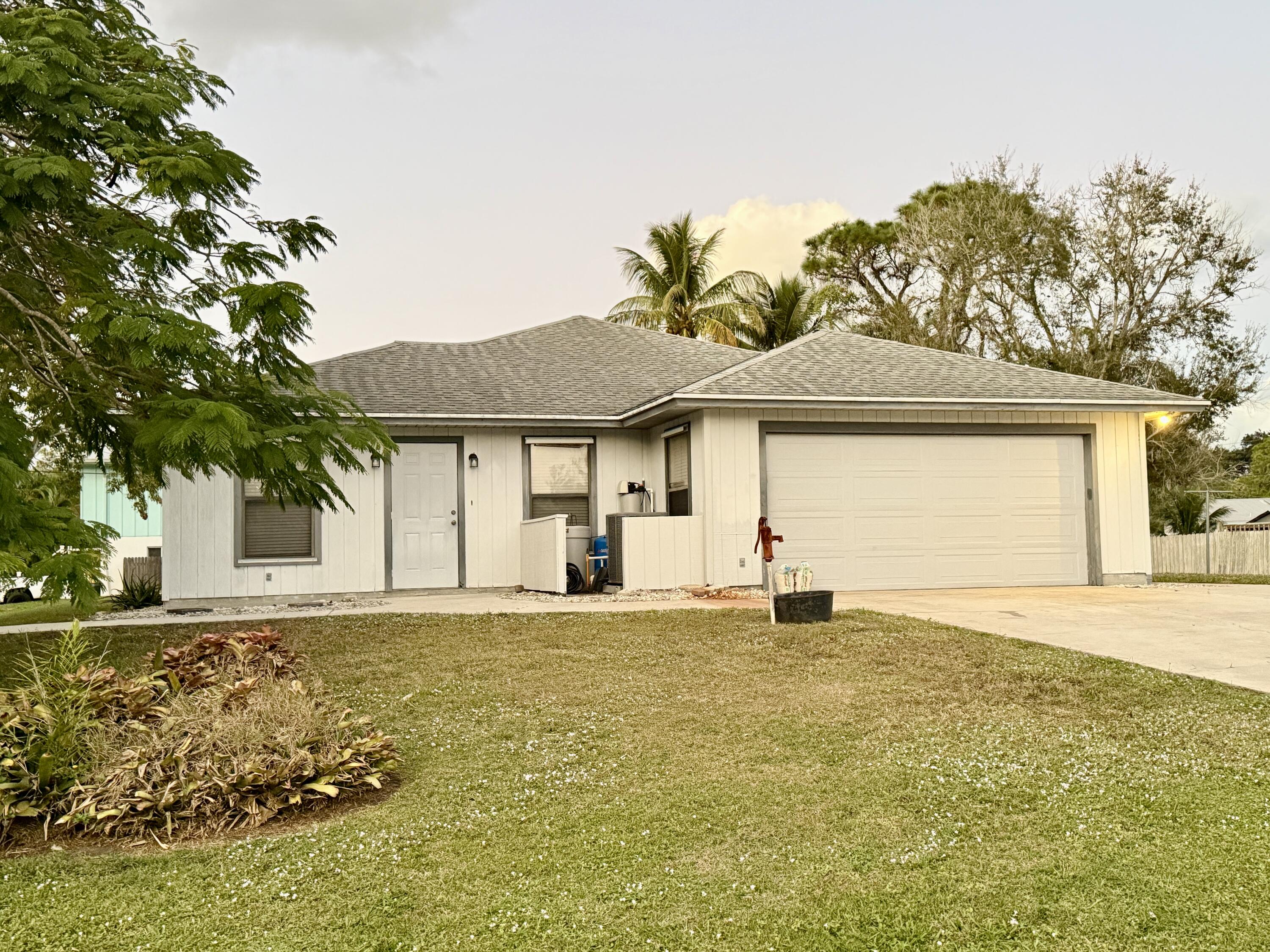 6539 Southeast Held Court Stuart, FL 34997 - Photo 32 of 34 a front view of a house with a garden and yard
