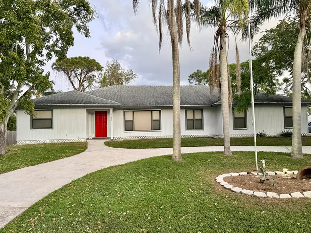 a view of a house with a yard and palm trees