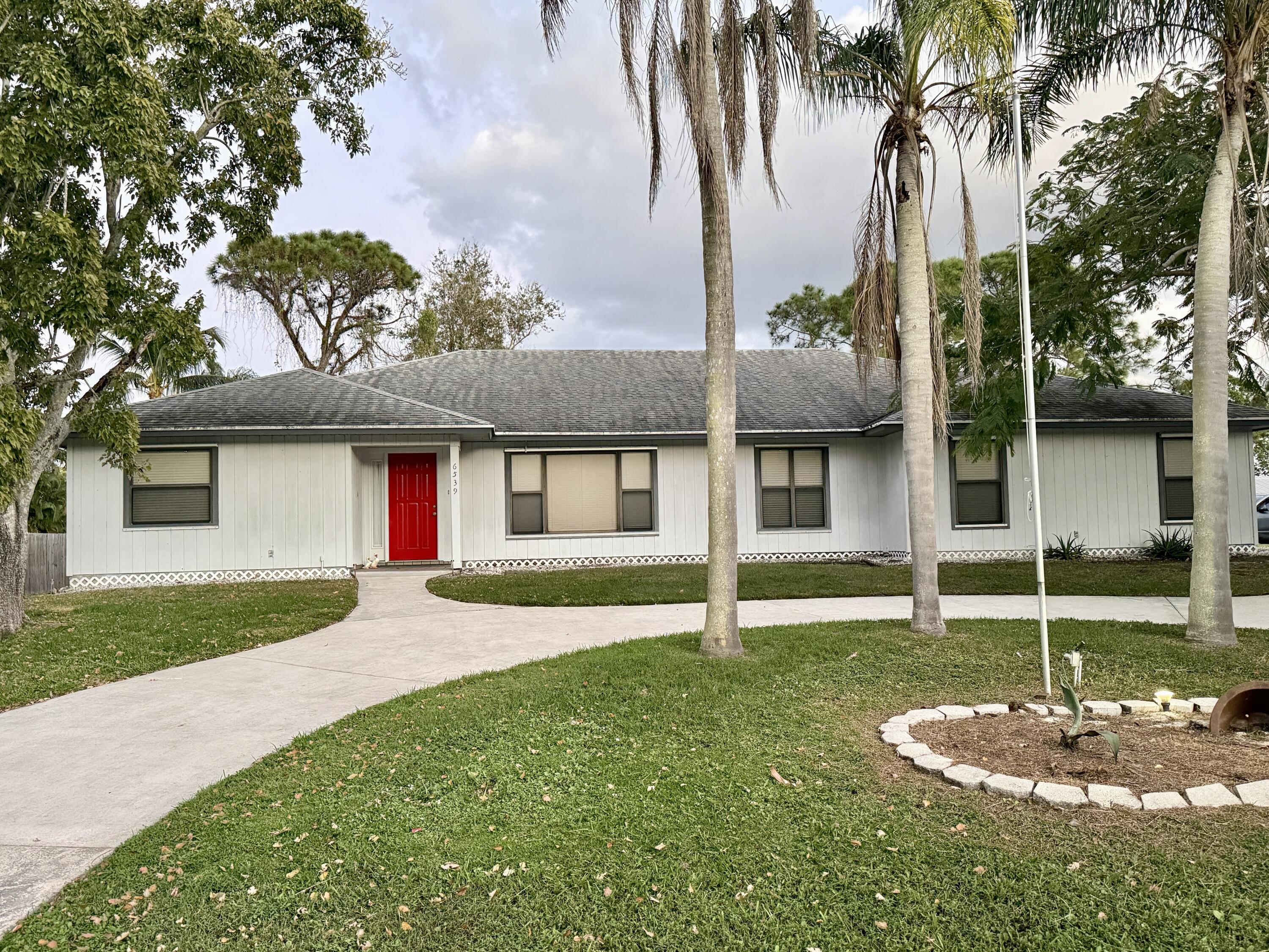 6539 Southeast Held Court Stuart, FL 34997 - Photo 33 of 34 a view of a house with a yard and palm trees