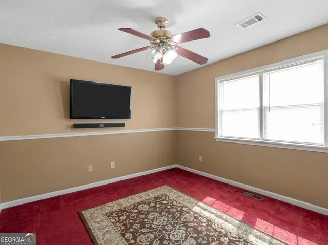 wooden floor in an empty room with a window and a flat screen tv