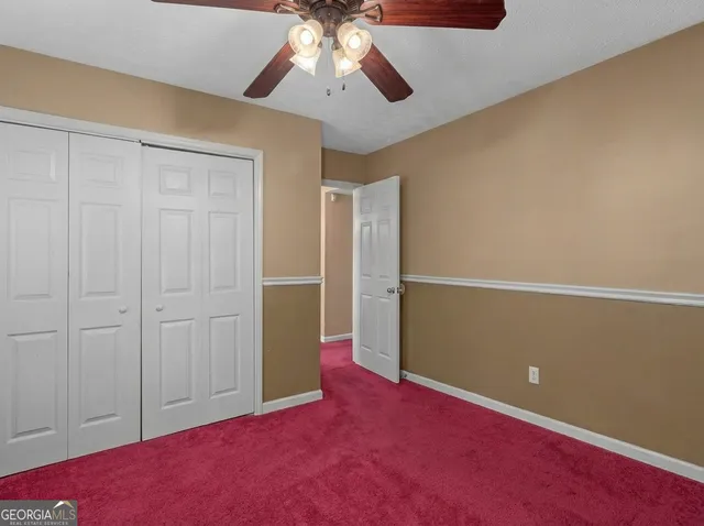 an empty room with closet and a chandelier fan