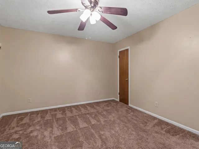 an empty room with a fan and a window