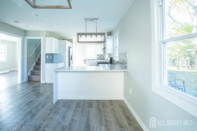 a kitchen with kitchen island white cabinets and wooden floor