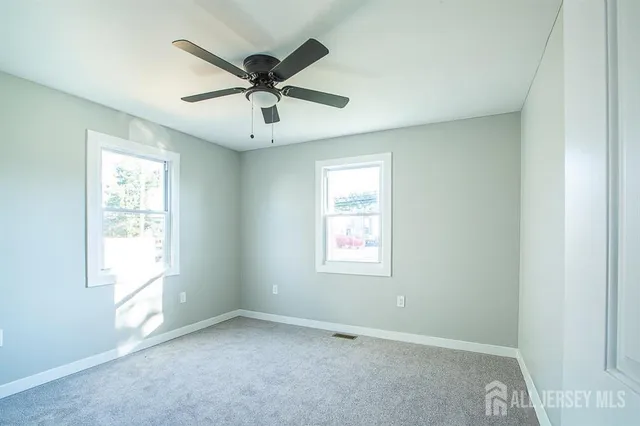 an empty room with windows and fan