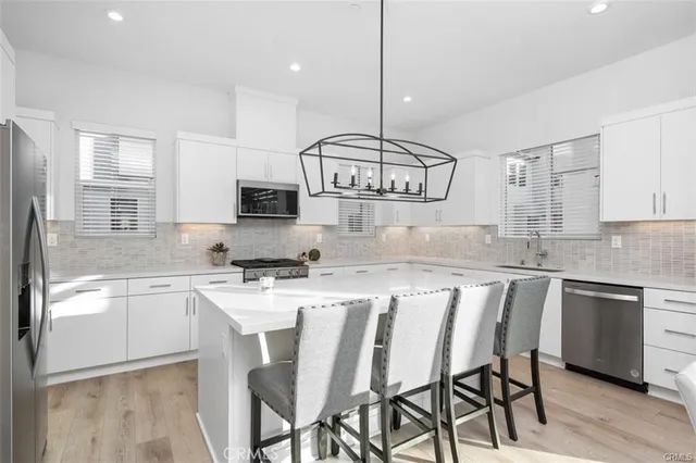 a kitchen with stainless steel appliances granite countertop a kitchen island a stove a sink a refrigerator and cabinets