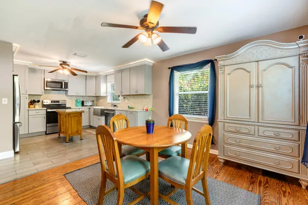 a kitchen with stainless steel appliances kitchen island granite countertop a table chairs and a refrigerator