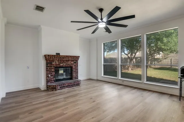 an empty room with wooden floor fireplace and windows