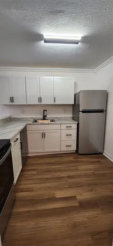 a view of kitchen with stainless steel appliances granite countertop a stove a sink and a refrigerator