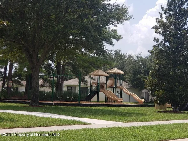 a view of a white house next to a yard with big trees
