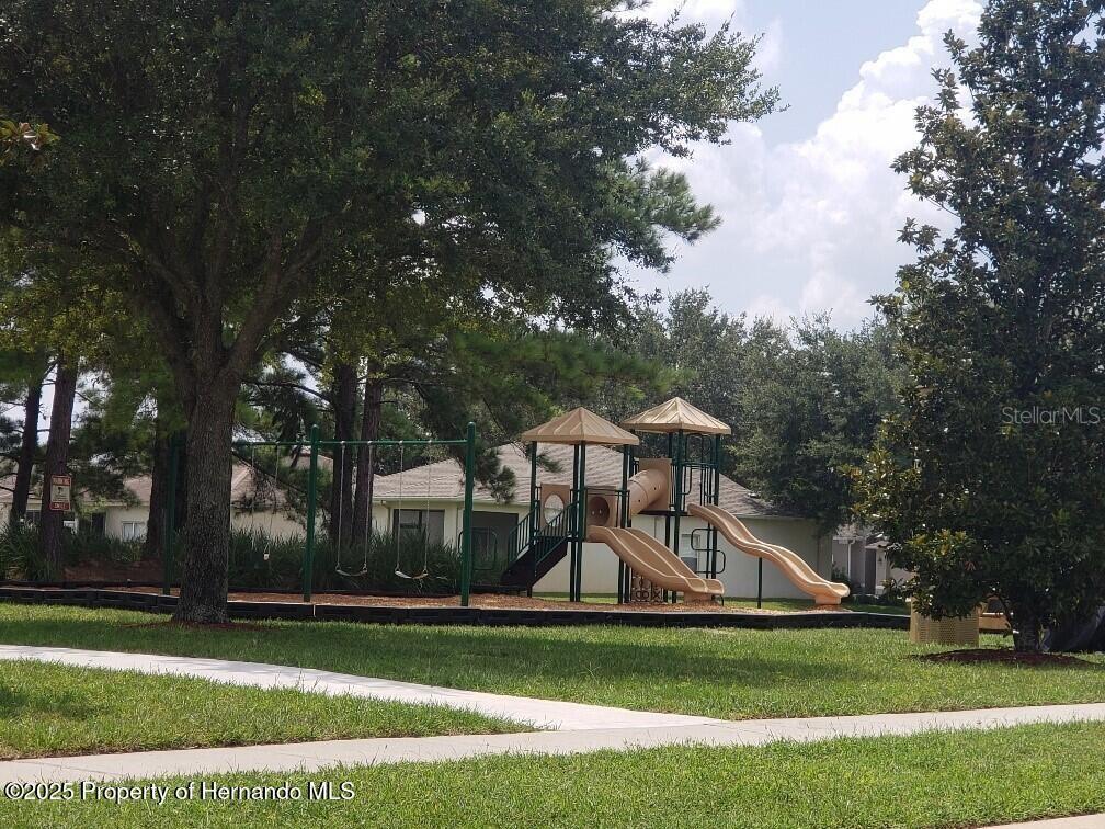 15206 Copper Loop Brooksville, FL 34604 - Photo 26 of 29 a view of a white house next to a yard with big trees