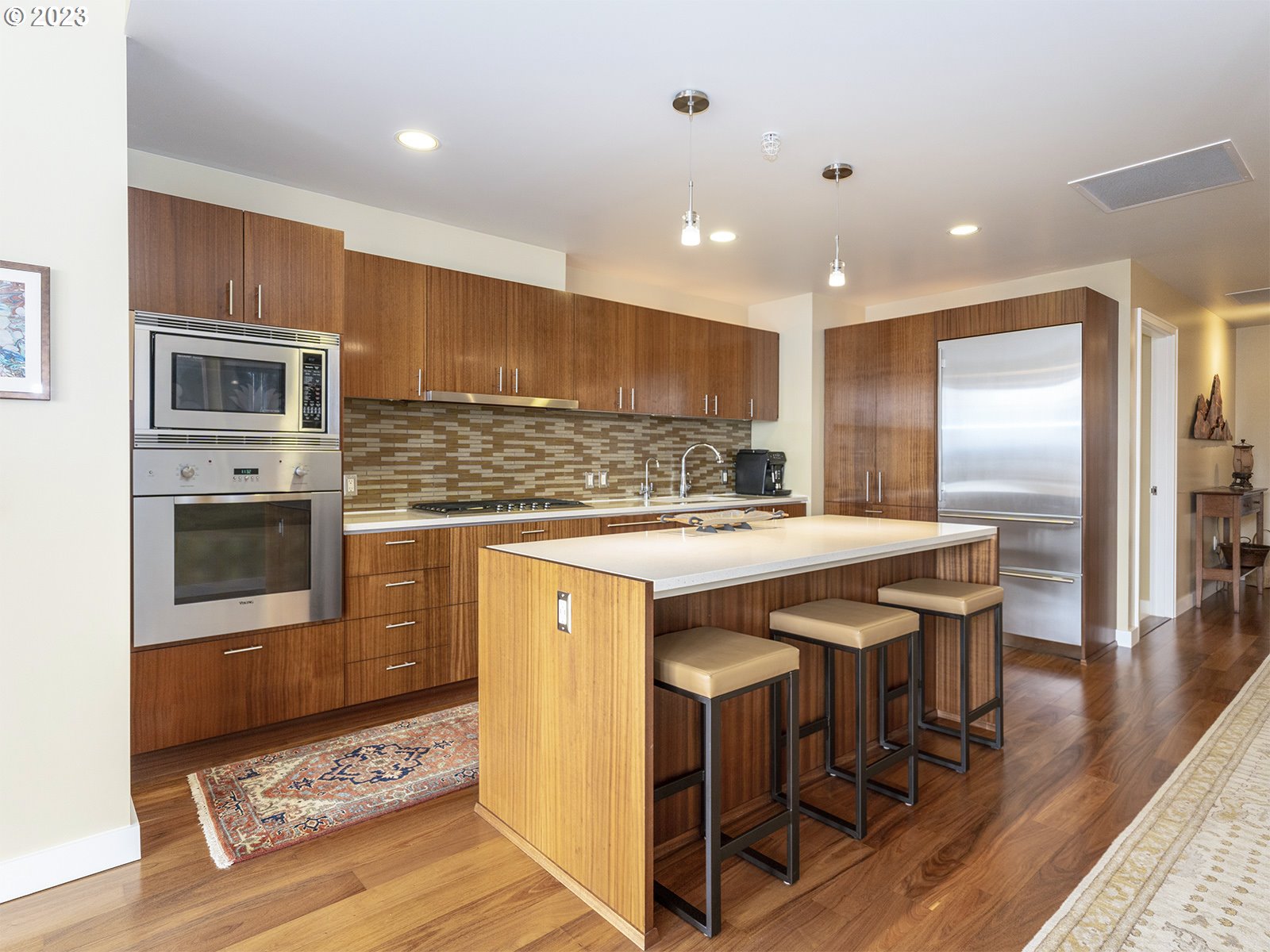 841 Southwest Gaines Street, Unit 1912 Portland, OR 97239 - Photo 8 of 32 a kitchen with kitchen island granite countertop wooden cabinets and stainless steel appliances