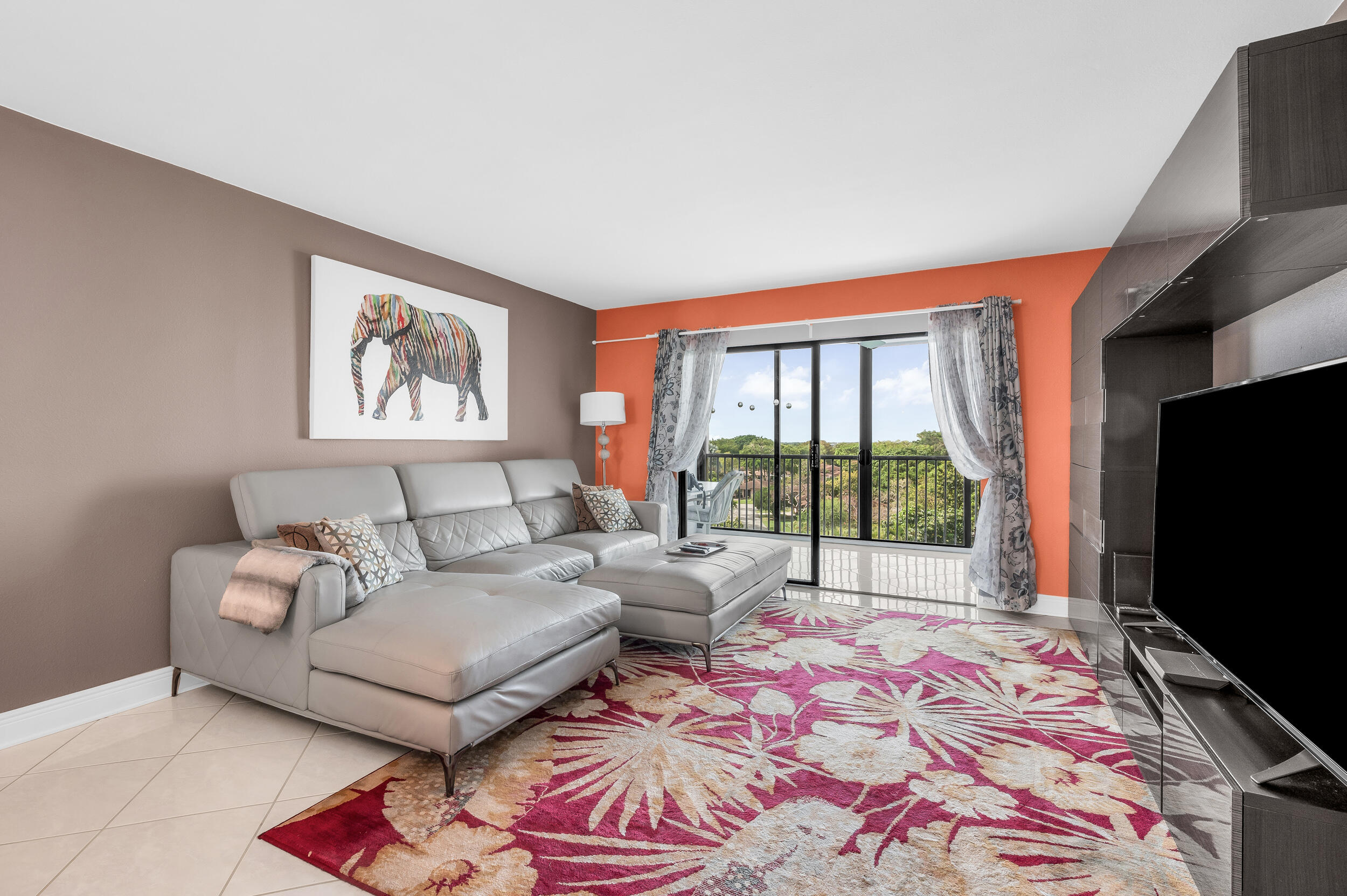 14475 Strathmore Lane, Unit 602 Delray Beach, FL 33446 - Photo 8 of 28 a living room with furniture a flat screen tv and a floor to ceiling window