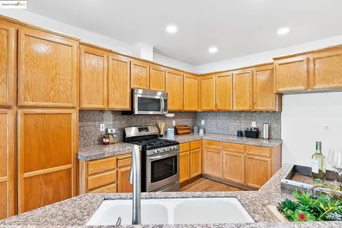 a kitchen with granite countertop a stove top oven sink and cabinets