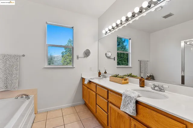 a spacious bathroom with a granite countertop sink a large mirror and a bathtub