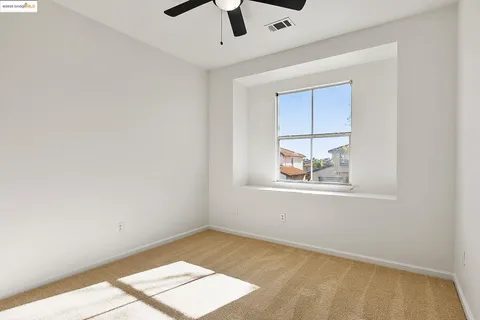 an empty room with a window and ceiling fan
