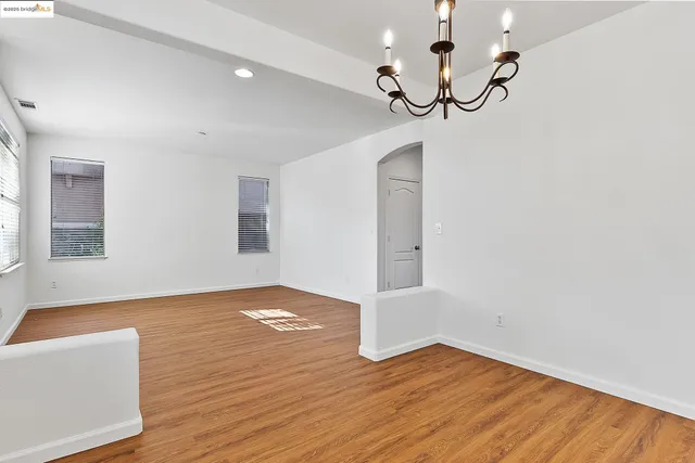 a view of empty room with wooden floor and ceiling fan
