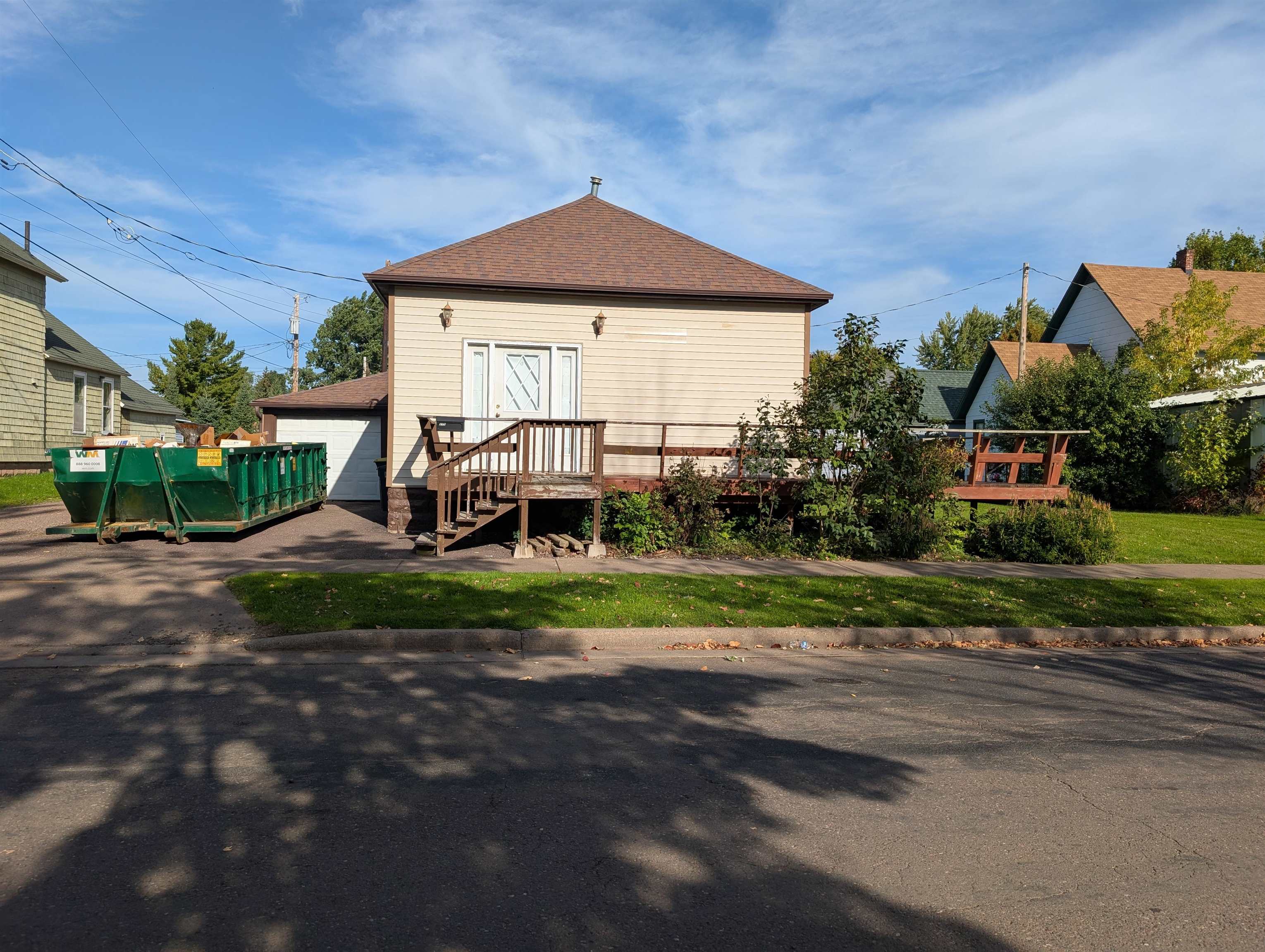 Back of property featuring roof with shingles, an outbuilding, and a garage