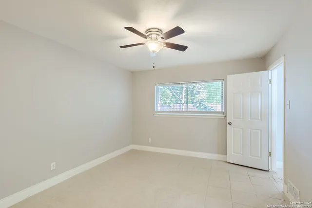 an empty room with a window and a ceiling fan
