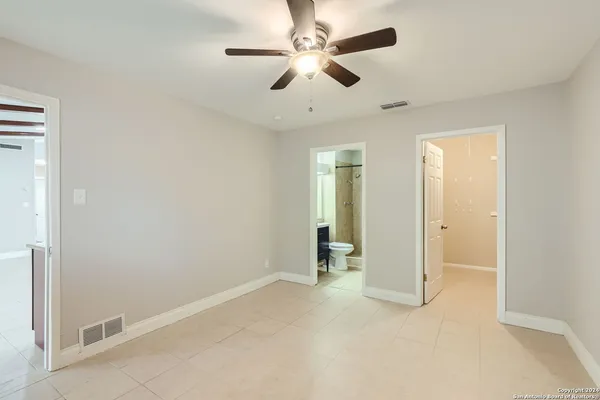 an empty room with chandelier fan and windows
