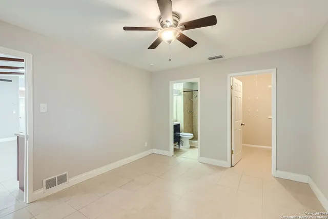 an empty room with chandelier fan and windows