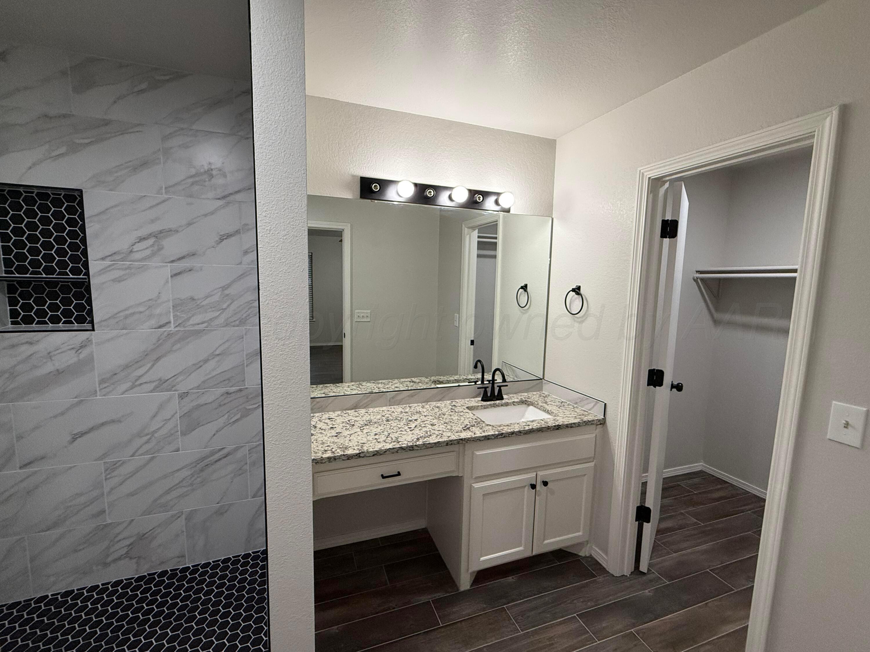 4914 Capulin Lane Amarillo, TX 79110 - Photo 13 of 25 a en suite bathroom with a granite countertop sink and a mirror