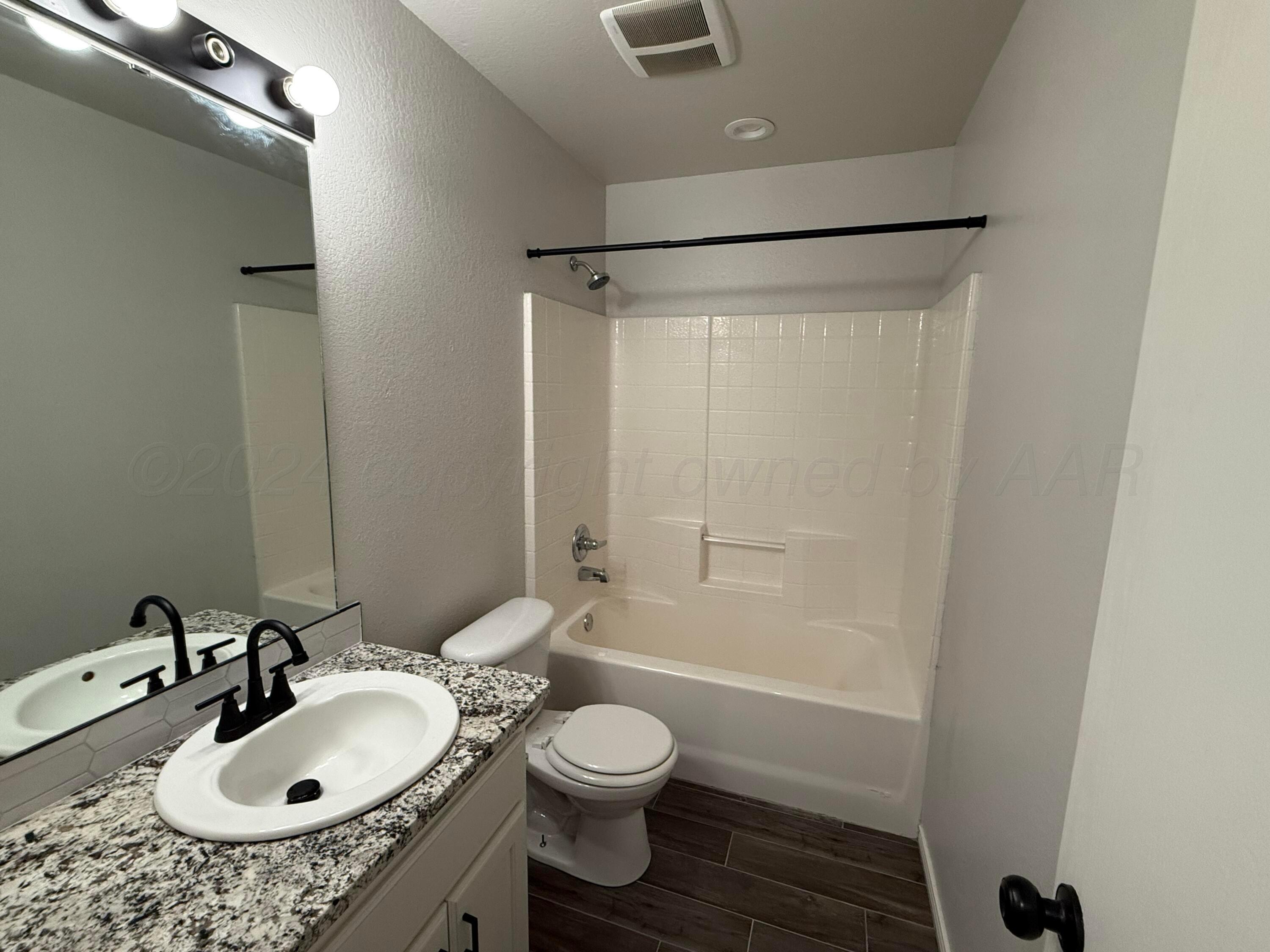 4914 Capulin Lane Amarillo, TX 79110 - Photo 20 of 25 a bathroom with a granite countertop sink a toilet and shower