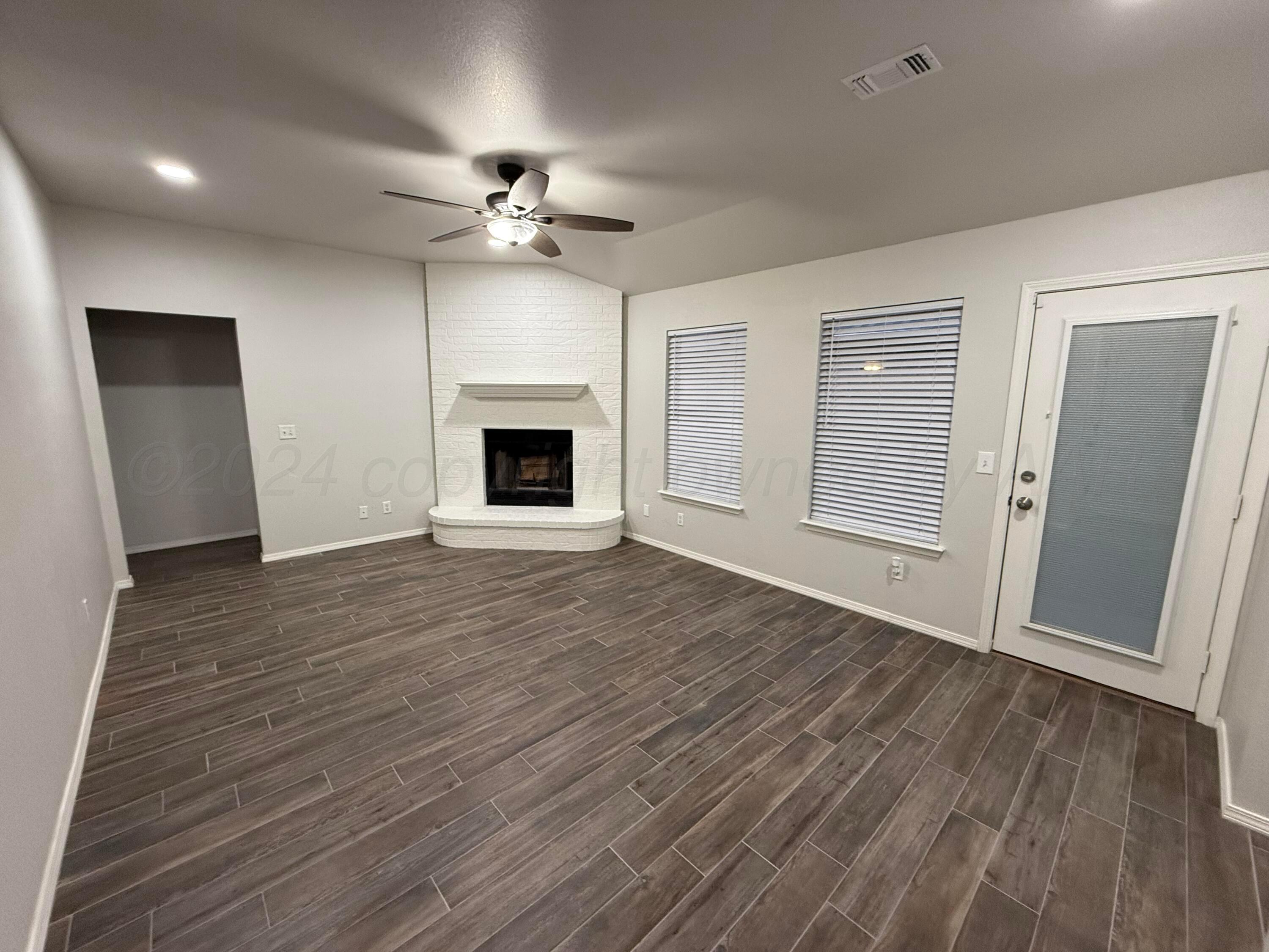 4914 Capulin Lane Amarillo, TX 79110 - Photo 2 of 25 a view of an empty room with wooden floor fireplace and a window