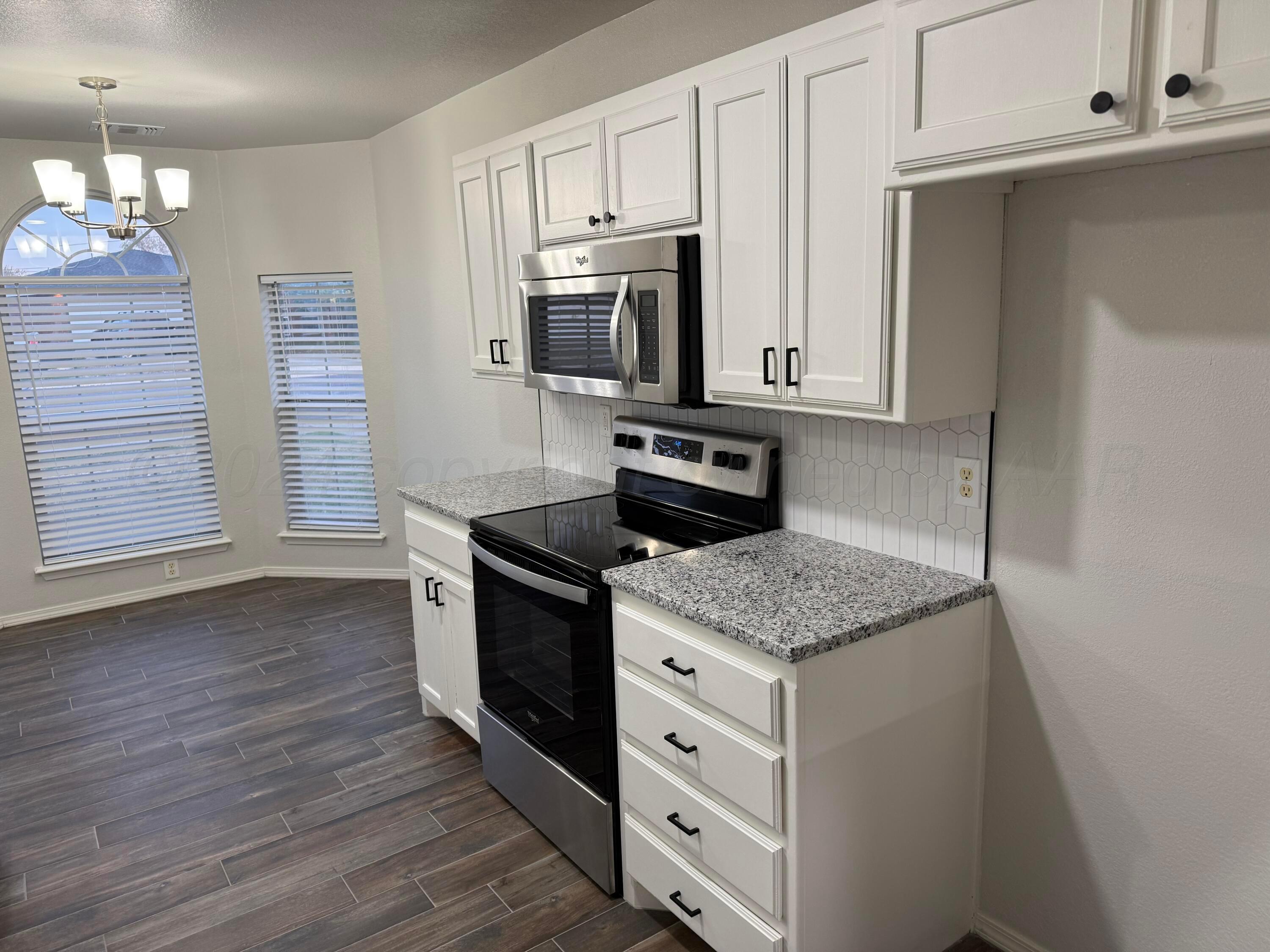 4914 Capulin Lane Amarillo, TX 79110 - Photo 5 of 25 a kitchen with granite countertop cabinets stainless steel appliances and a wooden floor