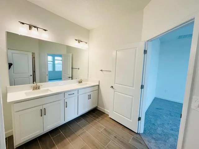 a spacious bathroom with a double vanity sink a mirror and a shower