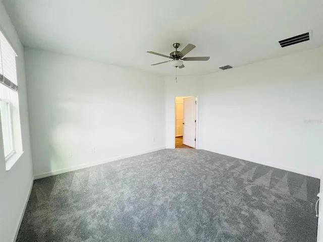 an empty room with a window and a fan