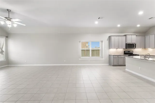 an empty room with chandelier fan and windows