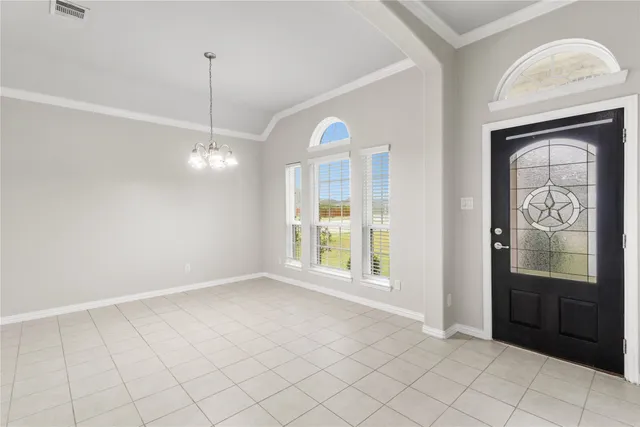 an empty room with chandelier fan and windows