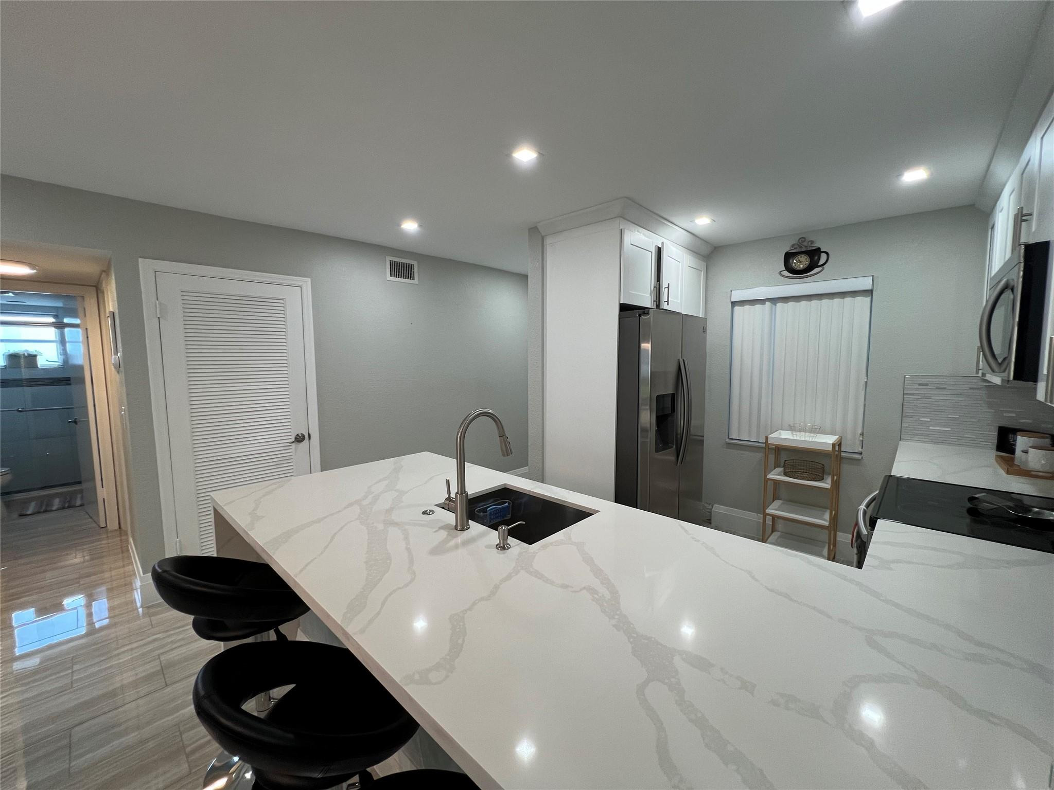 9780 Marina Boulevard, Unit 415 Boca Raton, FL 33428 - Photo 26 of 39 a kitchen with a table and refrigerator