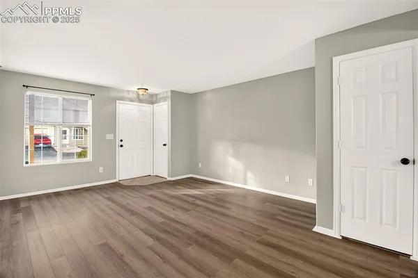 an empty room with wooden floor and windows