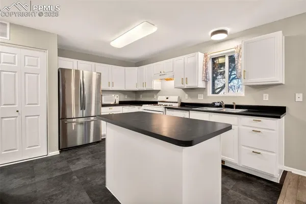 a kitchen with granite countertop a refrigerator sink and cabinets